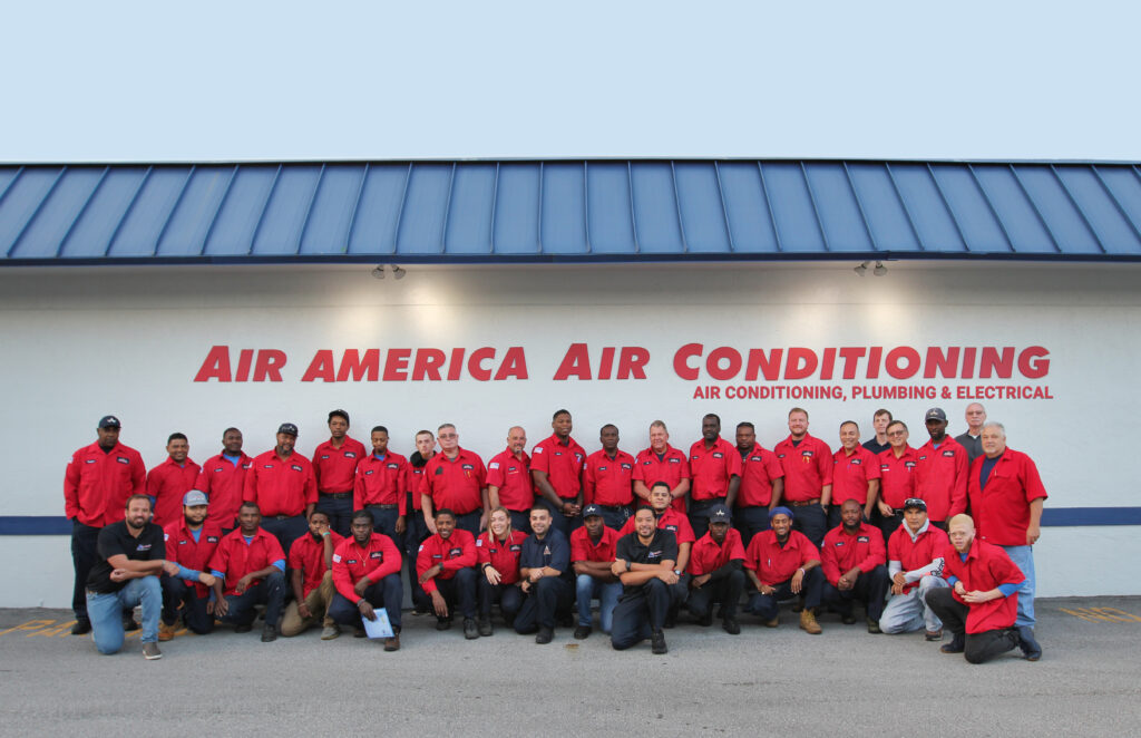 Air America team standing in front of the Air America logo on the side of a building.