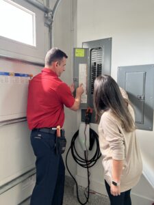 Technician and homeowner looking at electrical panel on wall