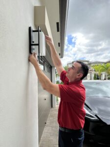 Tech in red shirt installing oudoor lighting on a home